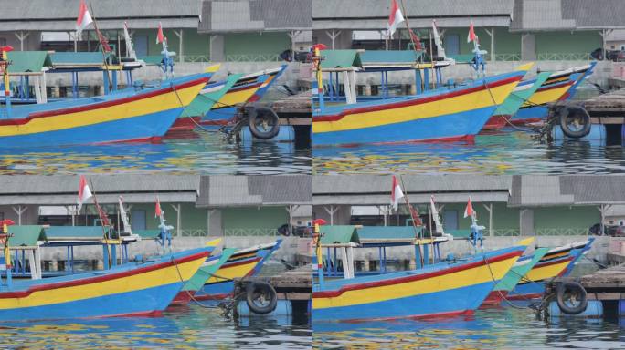挂着印尼国旗的彩色木制游船停泊在楠榜岛的沿海港口，在海浪中颠簸