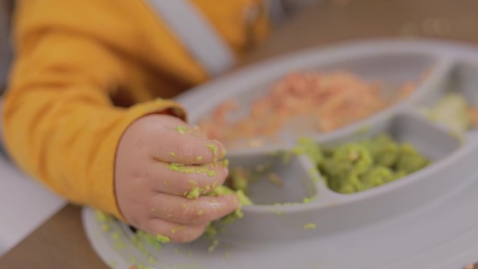 一个孩子的手从双酚a硅胶盘子里抓食物的特写