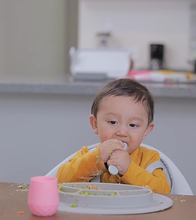 宝宝坐在桌子旁吃饭时弄脏了。婴儿补充喂养。BLW概念