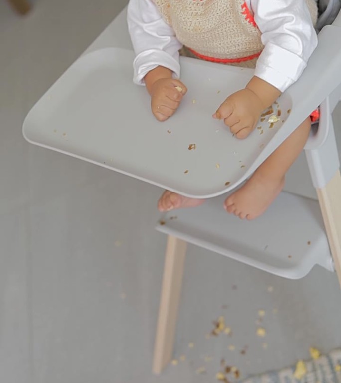 俯视图，一个男孩坐在椅子上吃东西时把食物扔在地板上