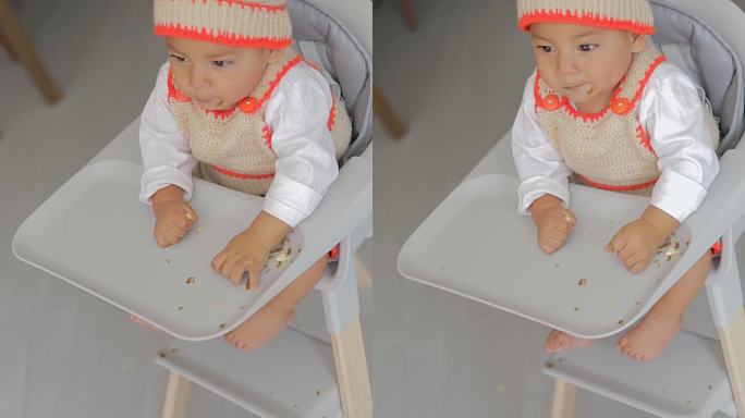 俯视图，一个男孩坐在椅子上吃东西时把食物扔在地板上