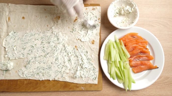 在皮塔饼上放上一层准备好的奶酪。准备鱼和蔬菜卷