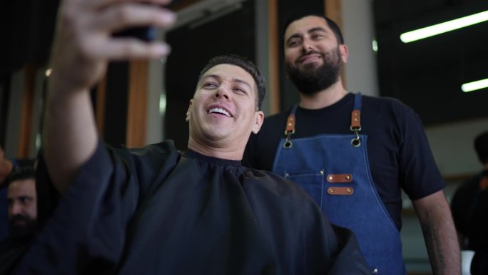 一名中年男子和他的理发师用手机为社交媒体录制视频