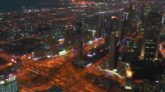 从哈利法塔拍摄的迪拜摩天大楼和繁忙的街道。傍晚现代城市的鸟瞰图。傍晚的城市灯光。