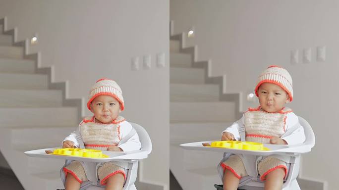 宝宝在家里的客厅里，坐在椅子上吃东西时做手势