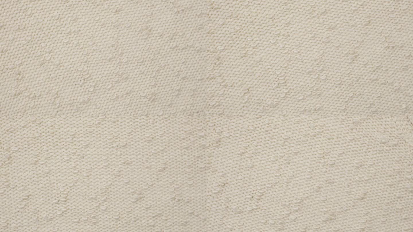 柔软的针织羊毛详细的纹理。天然织物近距离针织图案。采购产品米色针织品，暖羊绒表面。旋转,宏。舒适的奶