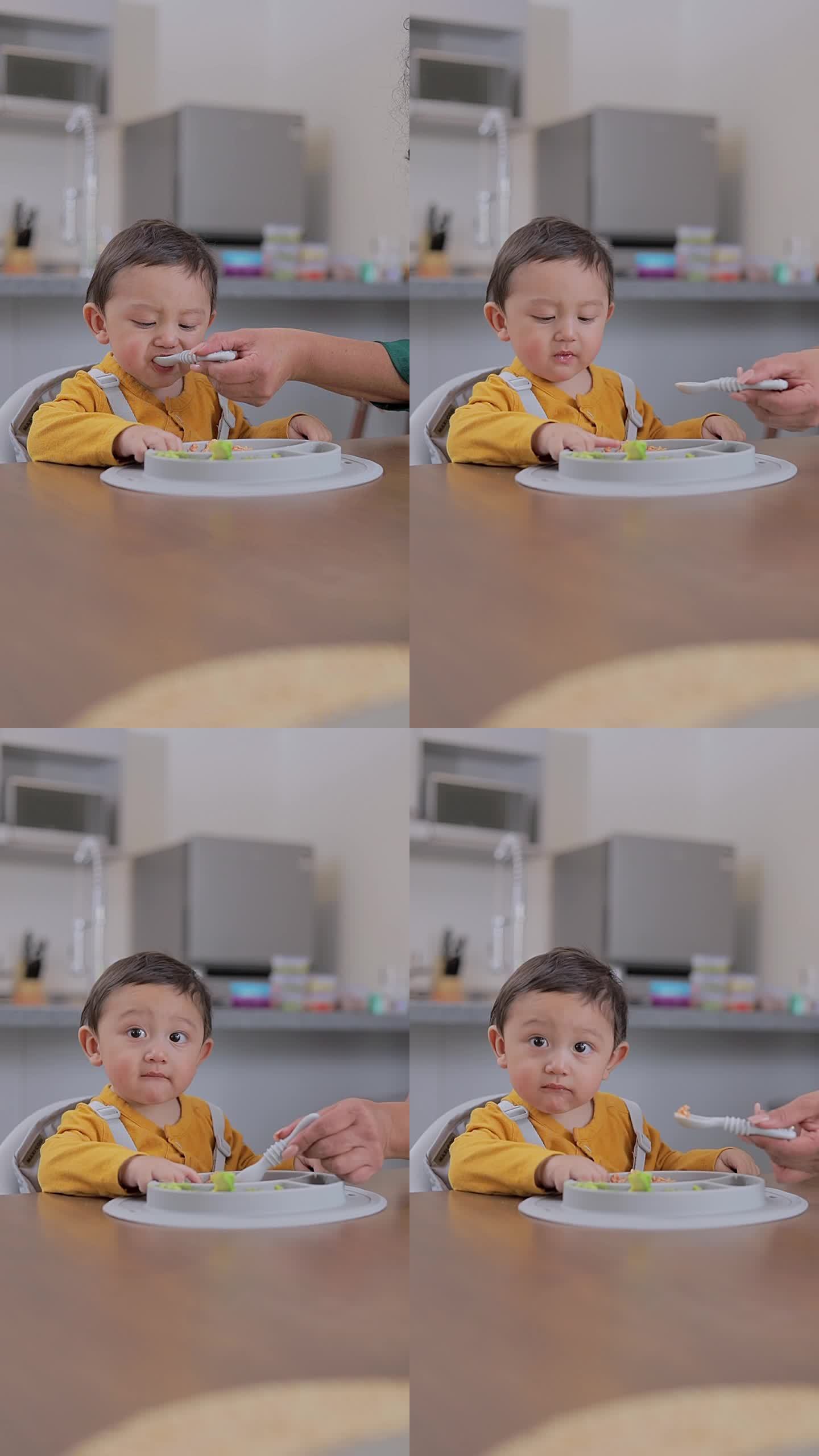 一个婴儿坐在桌边被用勺子喂的特写。婴儿主导的断奶概念。补充喂养