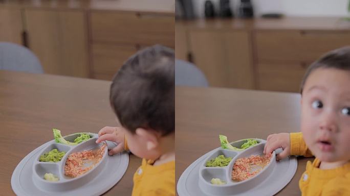 一个盛着食物的吹盘子的俯视图，而一个孩子正在吃。婴儿主导的断奶概念