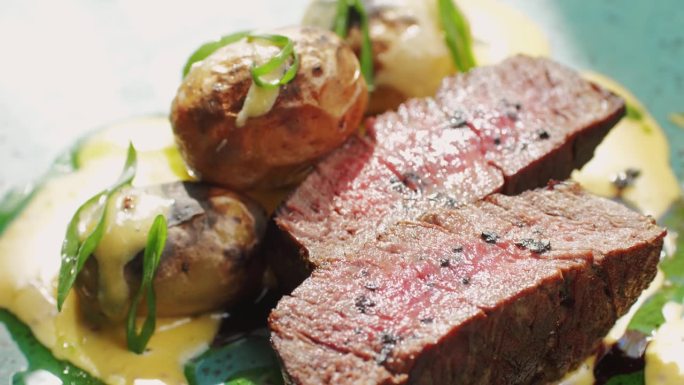 在昂贵的现代融合餐厅里，多汁的中牛肉肉肋眼牛排片配烤土豆，近距离享用精致的晚餐。