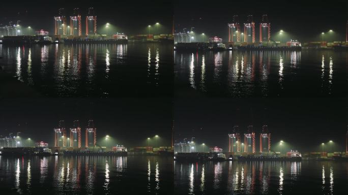 夜晚港口的景象与货物集装箱起重机，灯光反射在水中。月光下集装箱货物作业，吊车活跃。平静的水面映照出正