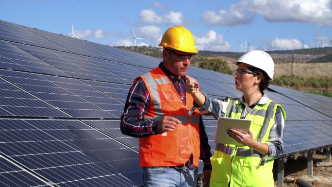 太阳能电池板，与人握手言和，合作或感谢安装绿色能源发电。年轻的成年工程师检查太阳能电池板的安装情况。