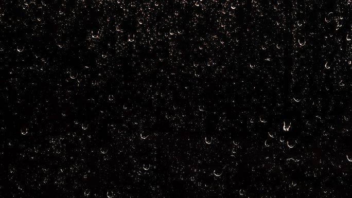 夜雨的水珠顺着黑色的玻璃流下来