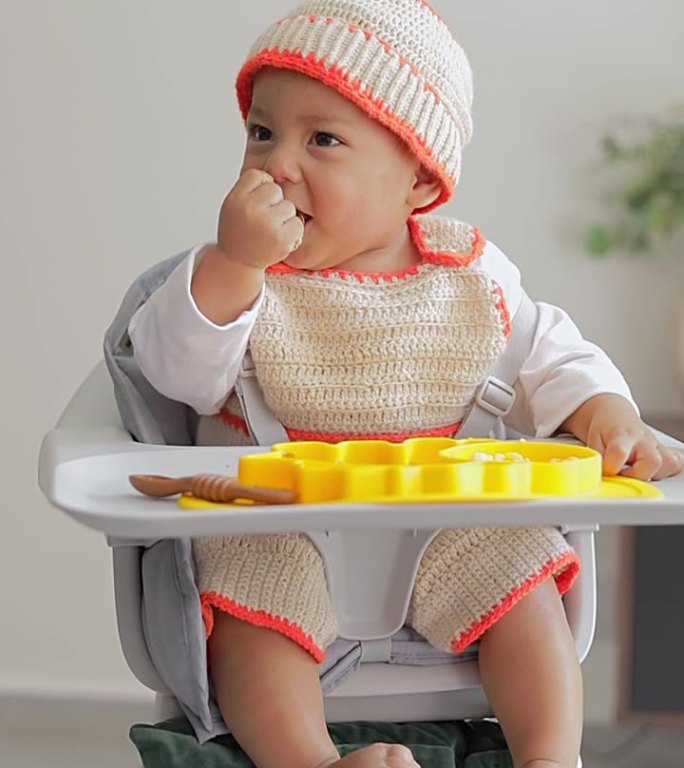 宝宝坐在椅子上边吃边笑。婴儿补充喂养