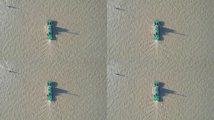 在阳光明媚的日子里，挖泥船在河上航行的高角度视图，它的影子在水面上，无人机俯视图，4k实时镜头。