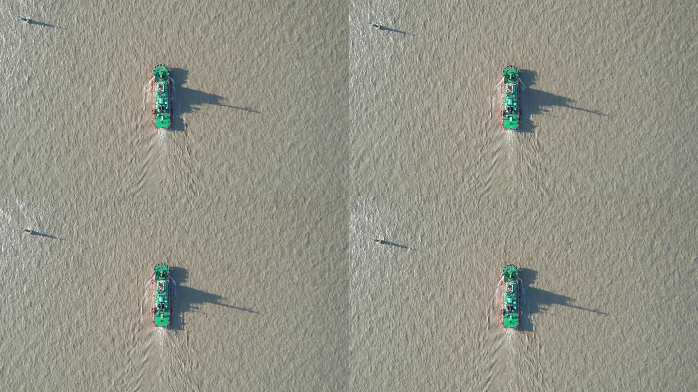 在阳光明媚的日子里，挖泥船在河上航行的高角度视图，它的影子在水面上，无人机俯视图，4k实时镜头。