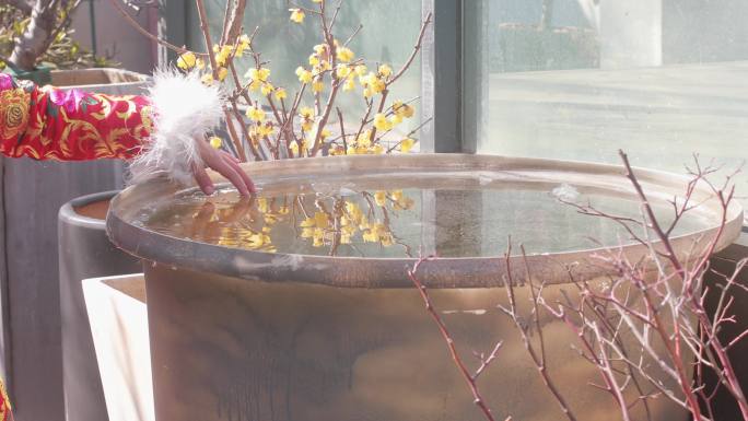 漂亮小女孩在院子捞桶里的冰块玩