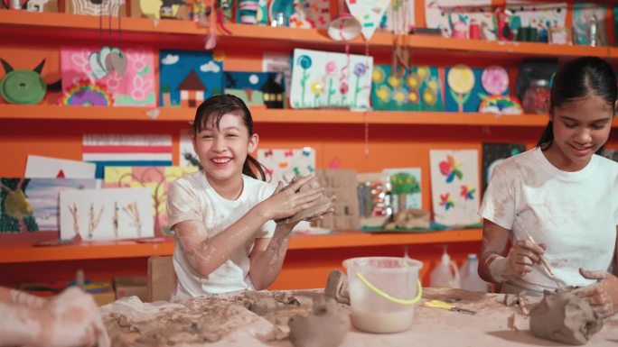 微笑快乐的高中女孩造型粘土与不同的朋友。启迪
