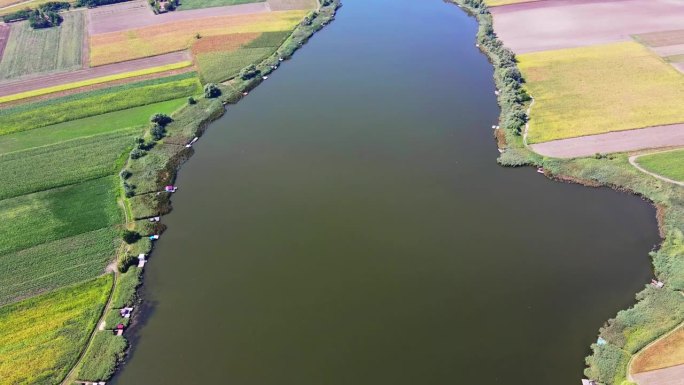 一架无人机在环绕着五颜六色的农田的大湖上空飞行
