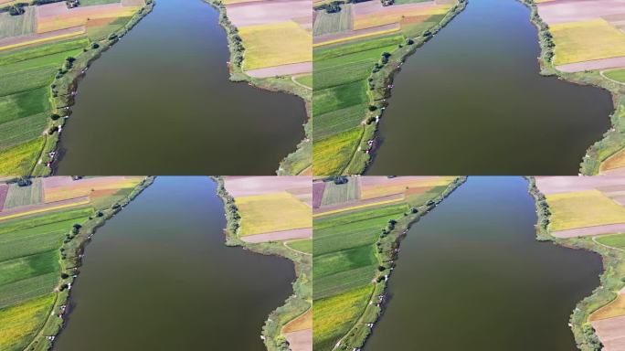 一架无人机在环绕着五颜六色的农田的大湖上空飞行