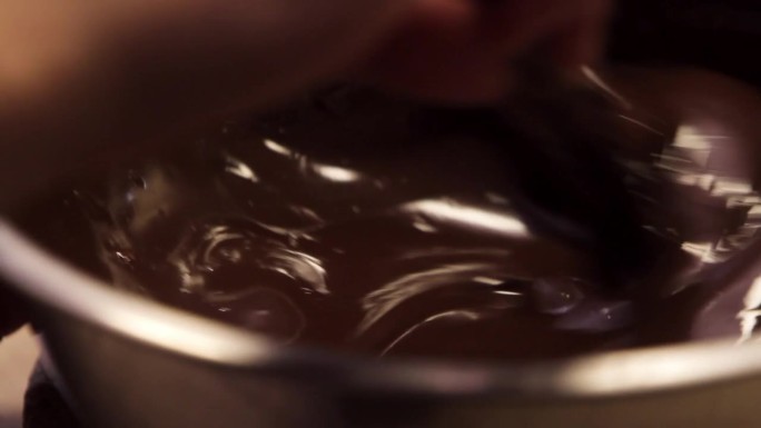 用木勺在锅中搅拌融化的液体黑巧克力