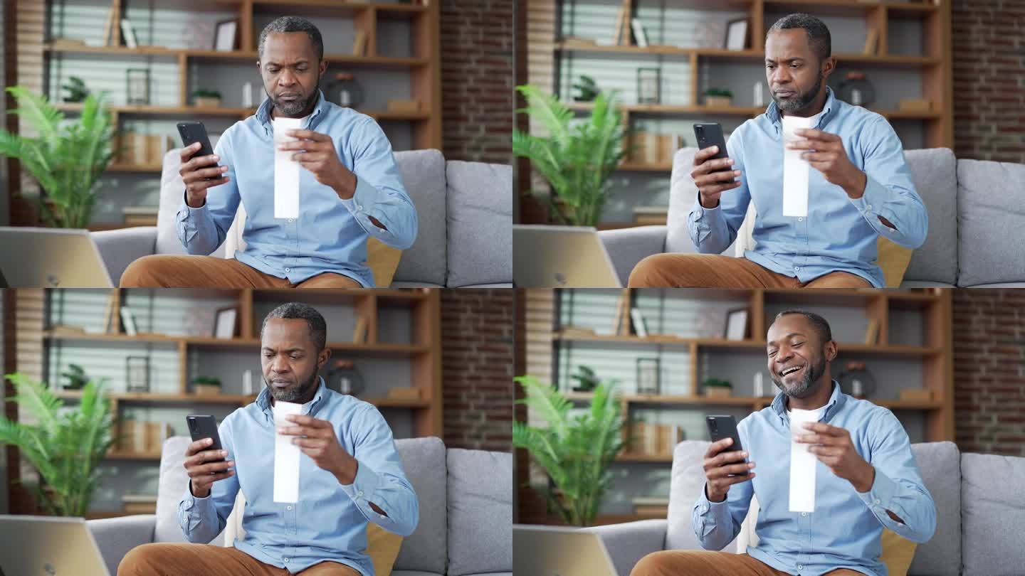 成熟的非裔美国人坐在房间里用智能手机支付水电费