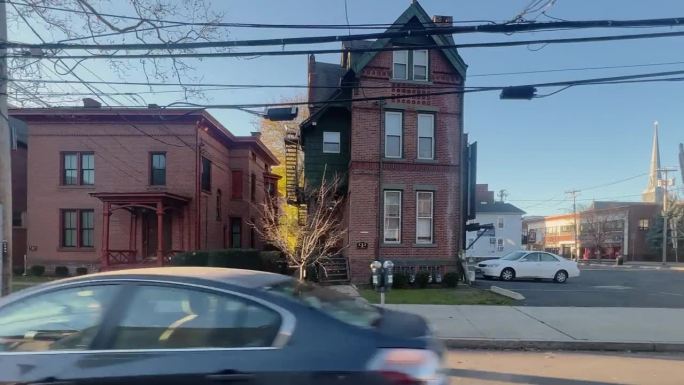 在一个晴朗、阳光明媚的日子里，康涅狄格州纽黑文的单户、多户和公寓式住宅的侧视图驾驶镜头