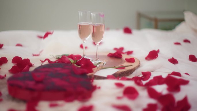 玫瑰花瓣落在情人节的卧室里，配上酒，慢动作