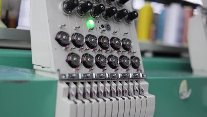 纺织厂的电子绣花机在工作过程中的侧视图，上面是五颜六色的线轴。专业的缝纫技术，习惯在织物上制作图案。