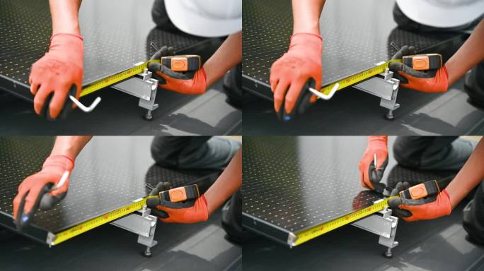 工人在搭建光伏太阳能电池板系统，用尺子测量安装设备。