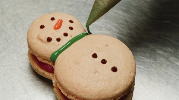 糖果师制作雪人形状的法式马卡龙甜点特写。夹心饼干，夹心饼干，夹心饼干。圣诞糖果。