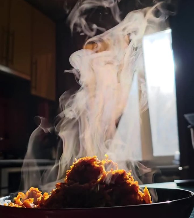 垂直的热蒸汽上升蔬菜粥胡萝卜炒洋葱特写很多蒸汽烟雾玻璃划痕桌子普通厨房的背景下，窗户阳光家庭烹饪