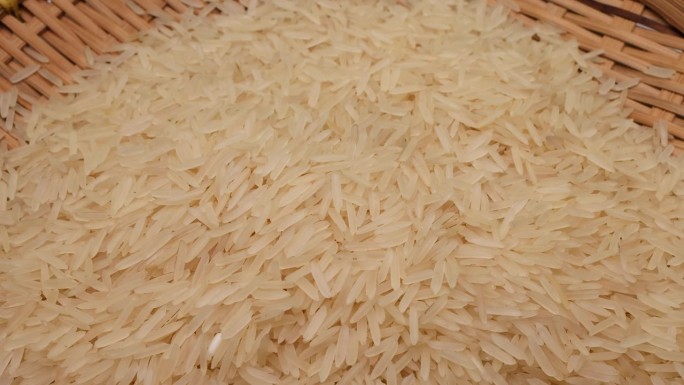 未煮熟的生白色长粒米倒落在竹盘旋转旋转锅