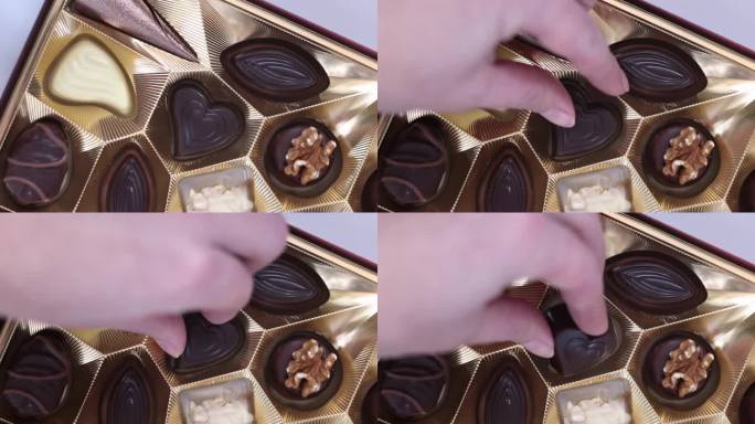 女孩从盒子里拿出一颗心形的巧克力糖。情人节概念