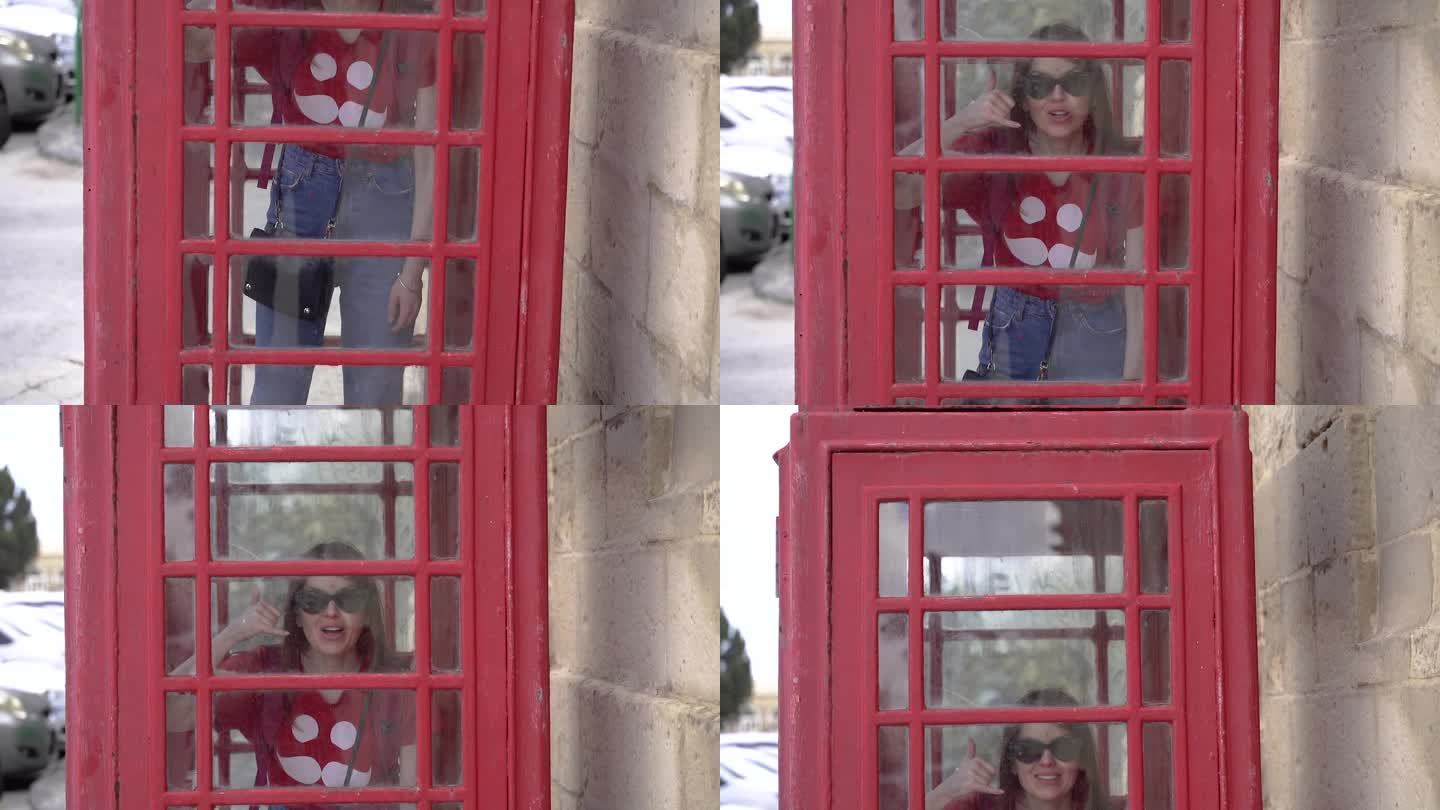 经典的红色电话亭。电话亭里的一个女孩。