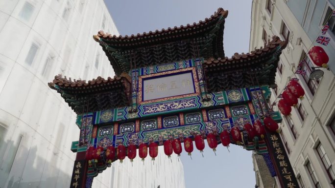 春日里，英国伦敦威斯敏斯特，一个人抬头看着挂着一串中国灯笼的唐人街大门