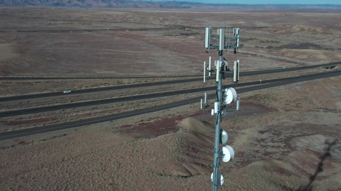 在一个阳光明媚的冬日，无人机在犹他州沙漠中靠近I-70的5G手机塔的近距离拍摄