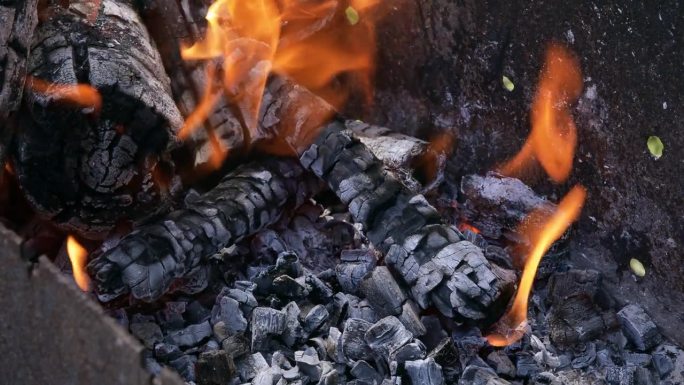 燃烧的煤特写。燃烧的火焰和黑色的柴火残余物。