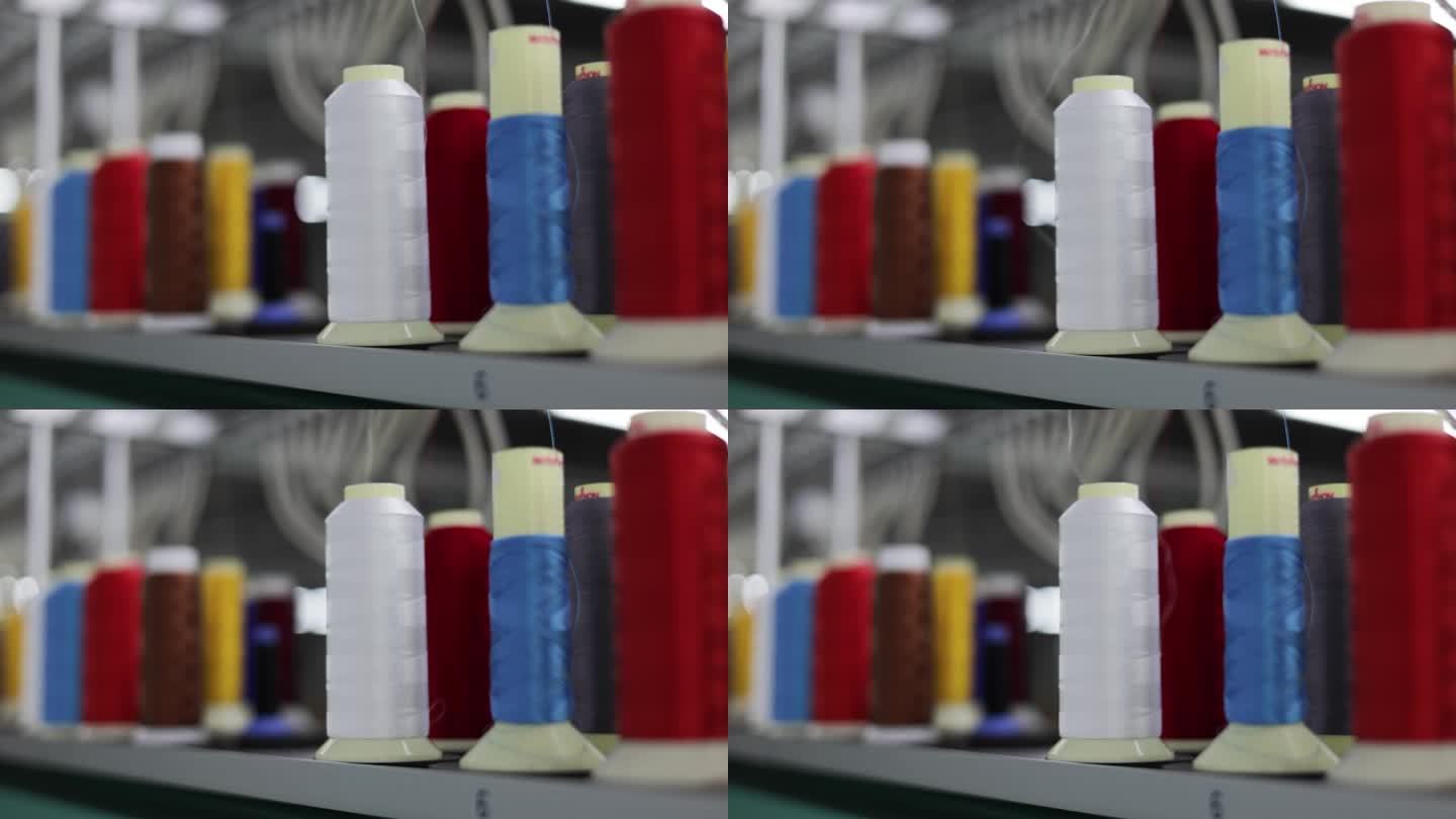 工业纺纱机彩色缝纫线轴和白色丝线的近照。多色筒子在服装生产行业的面料制造厂使用。