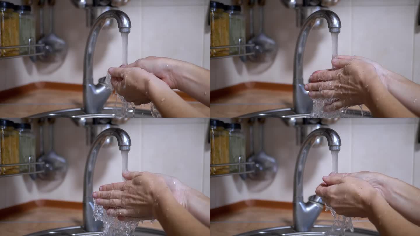 一名妇女在厨房里用流动的清水喷射器洗手