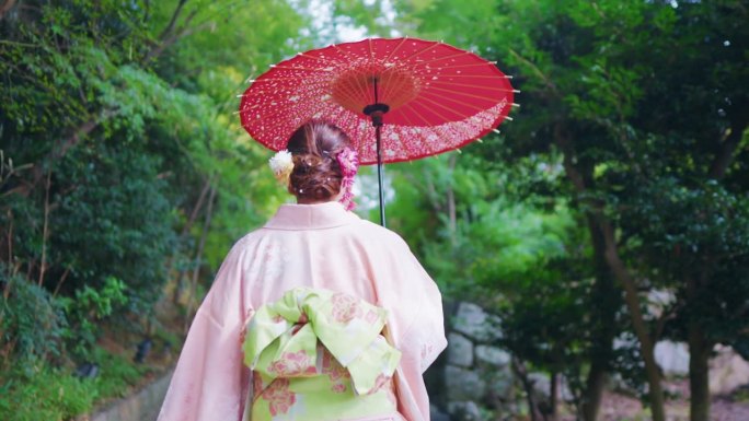 穿着日本和服的美女手持红色雨伞在森林风景中呼吸