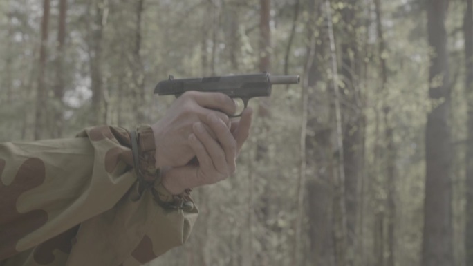 穿着迷彩服的士兵射击托卡列夫Tt-30手枪。特写苏联军队军服。森林秋天的战争。托卡列夫手枪被称为Tt
