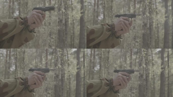 穿着迷彩服的士兵射击托卡列夫Tt-30手枪。特写苏联军队军服。森林秋天的战争。托卡列夫手枪被称为Tt