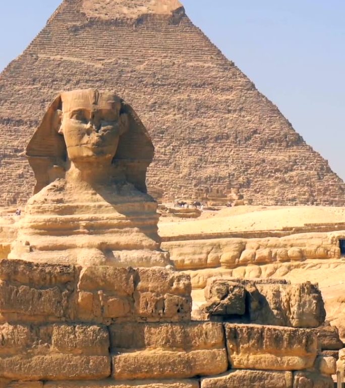一个年轻人穿着蓝色的衣服，戴着头巾，走在银座金字塔旁边的银座狮身人面像上。开罗,埃及