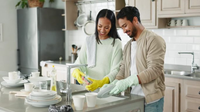 夫妻俩，一边聊天一边和厨房的水槽一起洗碗，在家里互相搀扶或开心地聊着笑话。男人，女人和团队合作的细菌