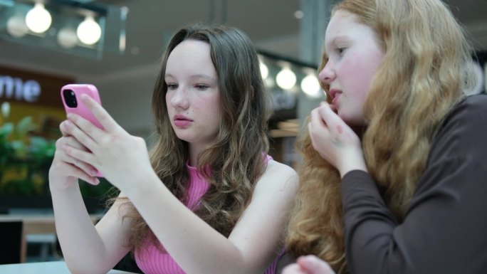 多民族学校女生课间在走廊玩智能手机。形形色色的女学生下课后一起在走廊用手机上网。