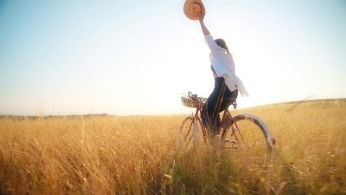 在阳光普照的草地上快乐地骑自行车的女人