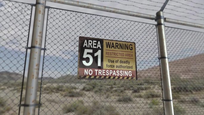 高质量的3D CGI渲染，在沙漠场景中一个秘密军事设施的铁链围栏上，有一个51区警告禁区的标志。