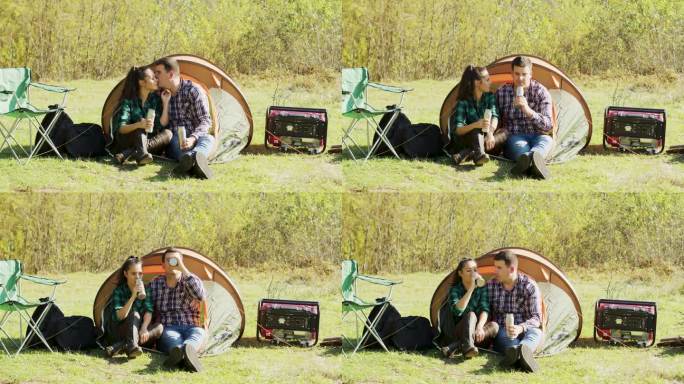 男友坐在他们的露营帐篷前亲吻女友的脸颊