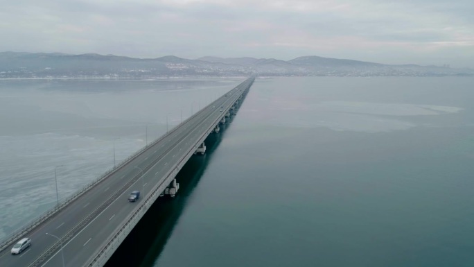 航拍的低水位桥横跨海湾与移动的汽车。运输车辆主动向不同方向移动。