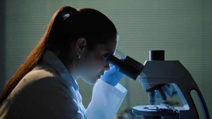 科学家、女性和学生在实验室用显微镜研究粒子、微生物或DNA测试。微生物学，科学和研究的数据分析，样品